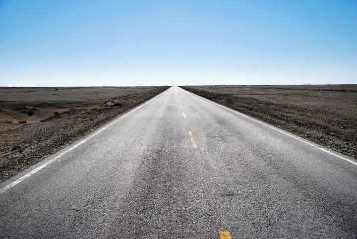 West of town, a two-lane road runs dead straight into the black gobi