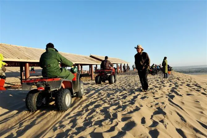 Quad bikes waiting under a shade roof at the dune edge