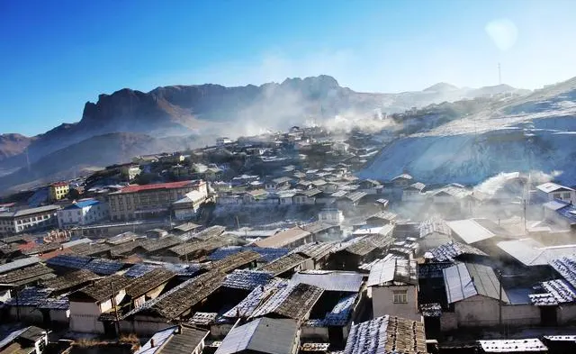 First snow on a Gannan town — flat roofs holding a crust, the ridge going white before the valley does