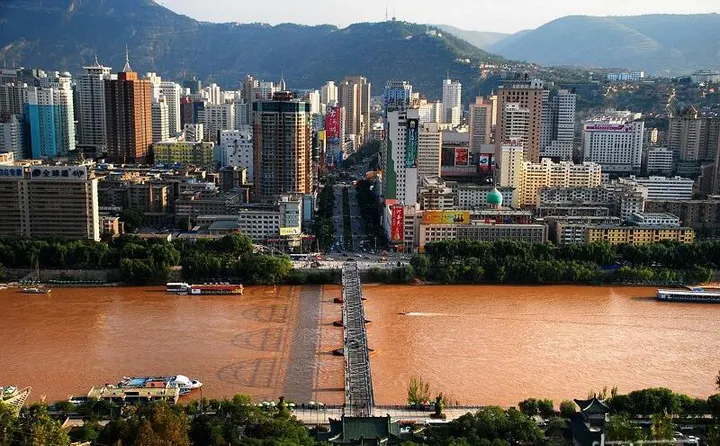 Lanzhou from above: the Yellow River through the middle, the iron bridge and the towers close on both banks — where every Gannan trip starts and ends