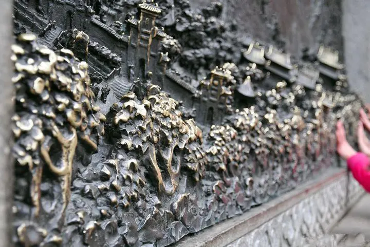 大庙里的一面铜刻：山、树、殿、塔一层层凸出来，铜面被手摸得发亮，右下角有一只手正贴着浮雕