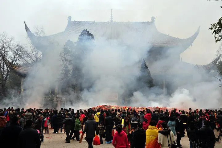 香期的大庙前院：人群围着一座长条香炉，火和烟一起往上走，后面的殿顶被烟遮掉一半