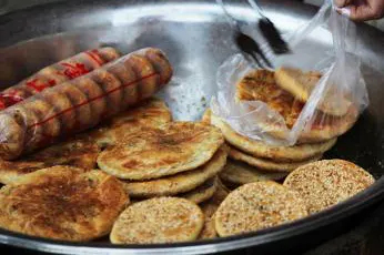 A griddle at a lane mouth: small cakes with dried mustard greens, baked against the side, ¥5 each