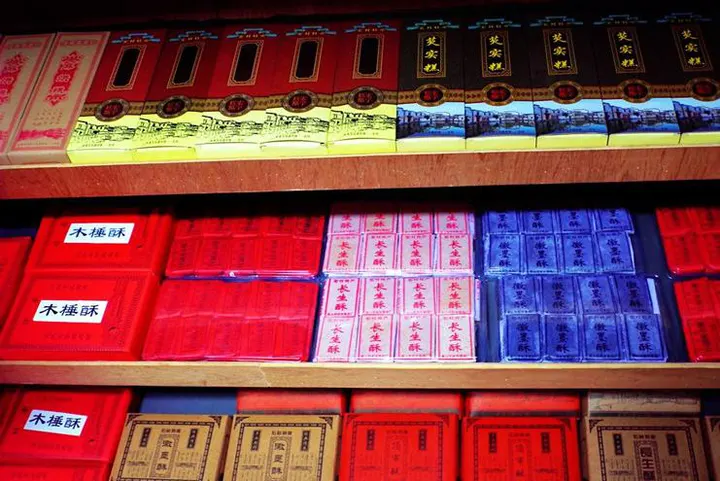 Shelves in a village shop: cakes, pastries and tea stacked in boxes to the ceiling