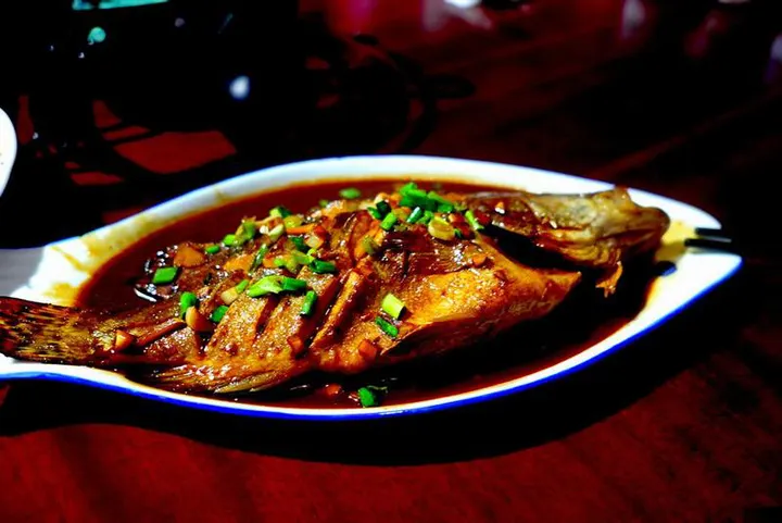 Stinky mandarin fish braised whole in a dark sauce, spring onion scattered over the top