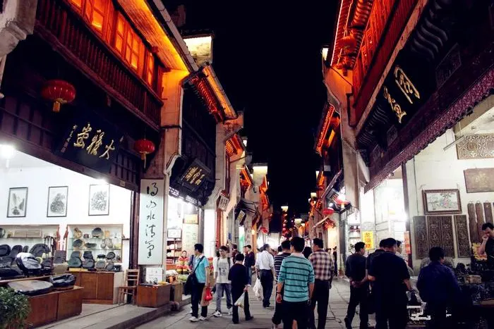 Tunxi Old Street after dark: timber shopfronts, red lanterns, stone paving, shops open past nine