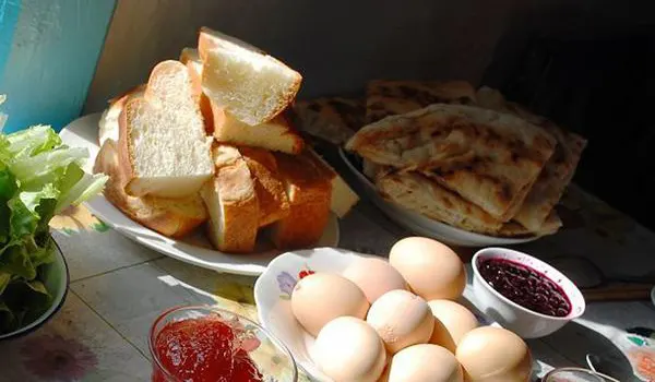 Breakfast at a family guesthouse — sliced loaf, fried flatbread, boiled eggs, blueberry jam and preserves