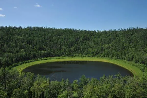 A crater lake — almost perfectly round, ringed the whole way by conifer forest