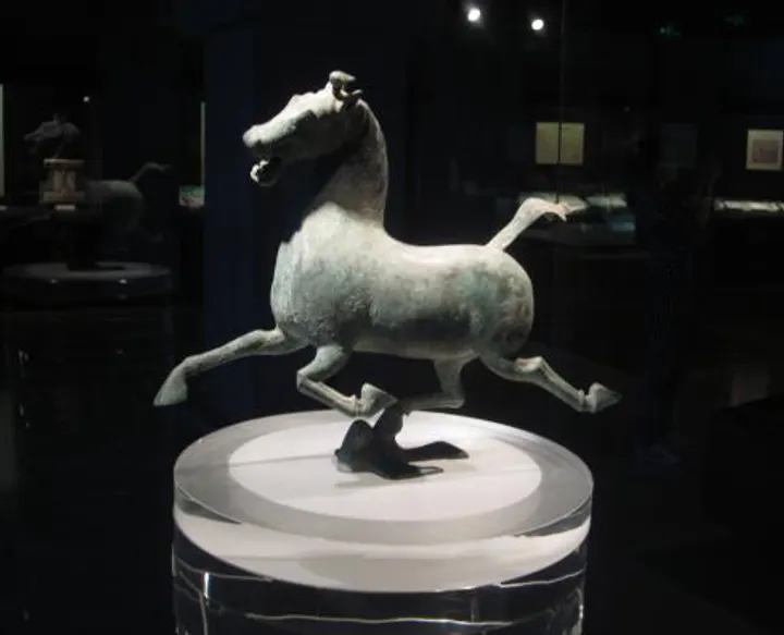 The Galloping Horse up close, three hooves airborne and one resting on a flying bird