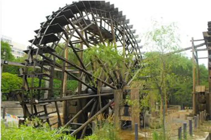A giant wooden waterwheel in the Waterwheel Park, its spokes towering over visitors
