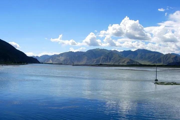 The Lhasa River — wide gravel flats, meltwater colour, mountains straight behind