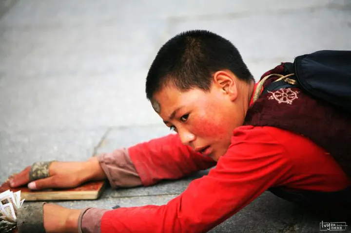 Mid-prostration, wooden boards strapped to the hands