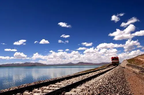 The railway running along a lake shore, ballast almost at the water