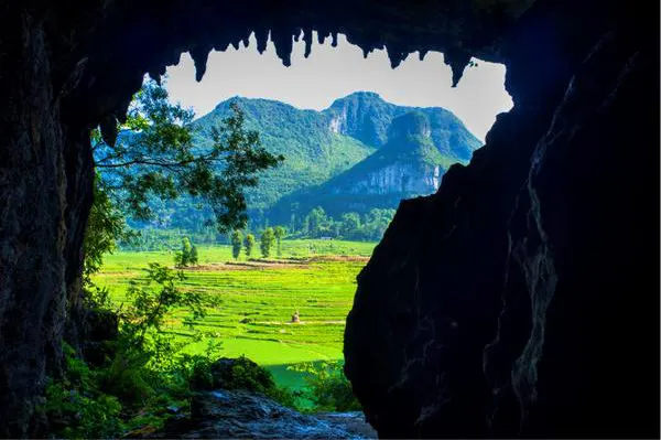 Looking out of Chuandong cave, the opening framing paddy fields and a cluster of cone peaks