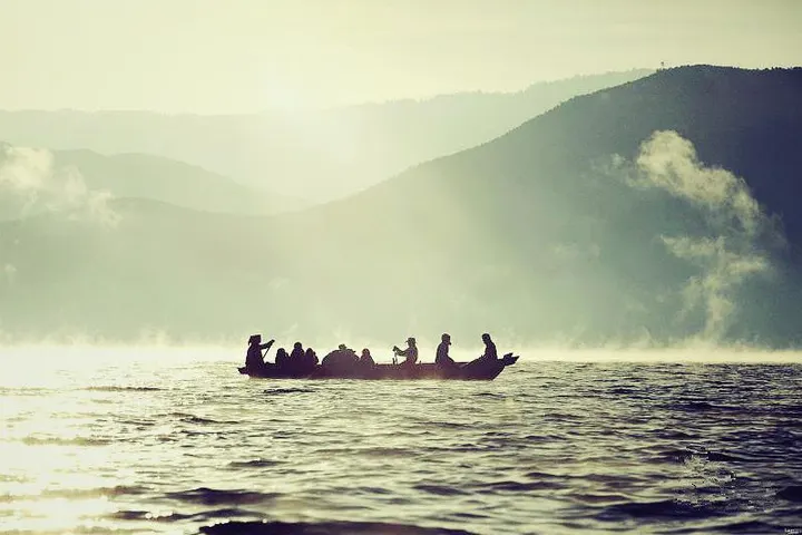 A full canoe in the morning mist, the ridges stepping away behind it