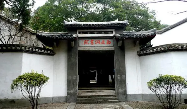 The academy gate — white walls, grey tiles, upturned eaves, its name carved above the door