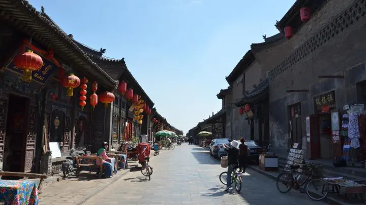 A street in the afternoon: bicycles, old shopfronts, lanterns overhead