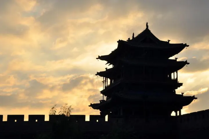 A gate tower reduced to silhouette in the last light