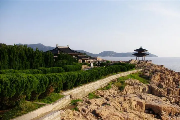 The coast path: clipped pine hedges and temple roofs on the left, rocks and water on the right
