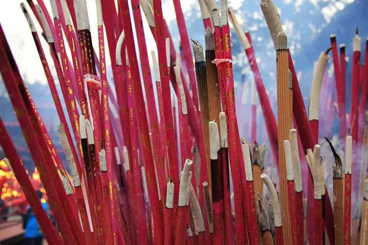 Incense in the burner, bundles at a time, red shafts showing beneath crowns of pale ash