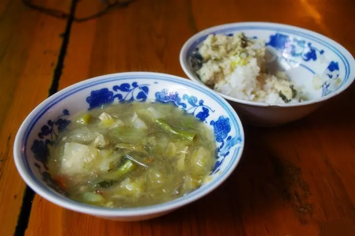 A refectory meal: cabbage and glass noodles in one bowl, rice in the other, blue-and-white porcelain on bare wood