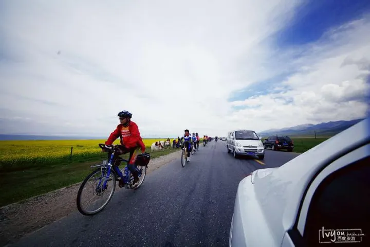环湖公路上的一队骑行者，后面跟着保障面包车；拍照的人坐在另一辆车里，右侧是白车车门
