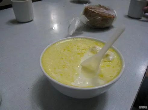 一碗老酸奶：表面结着一层淡黄色的奶皮，配一只塑料勺，旁边是塑料袋装的饼