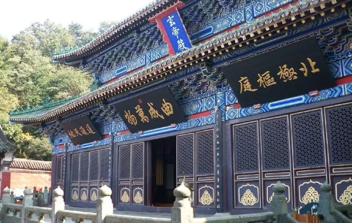 一处殿门：蓝绿彩画铺满整个檐下，门上悬三块黑底金字的匾，石栏一直围到台阶口