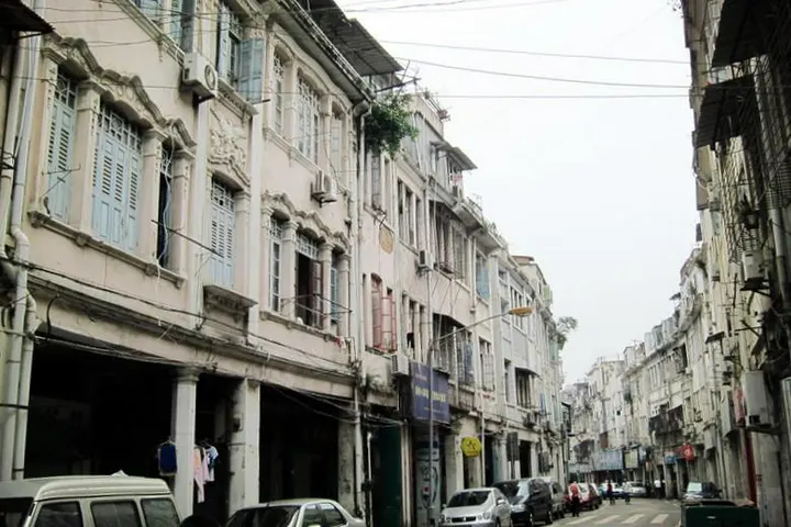 An afternoon street in the old town: arcades, banyan shade, small shopfronts