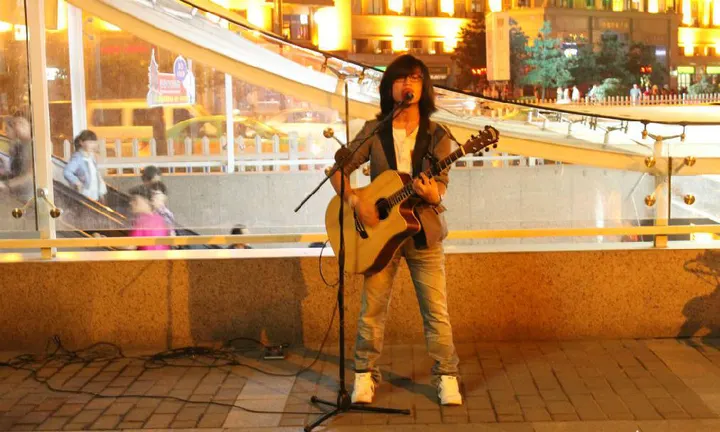 A street singer at the foot of the wall