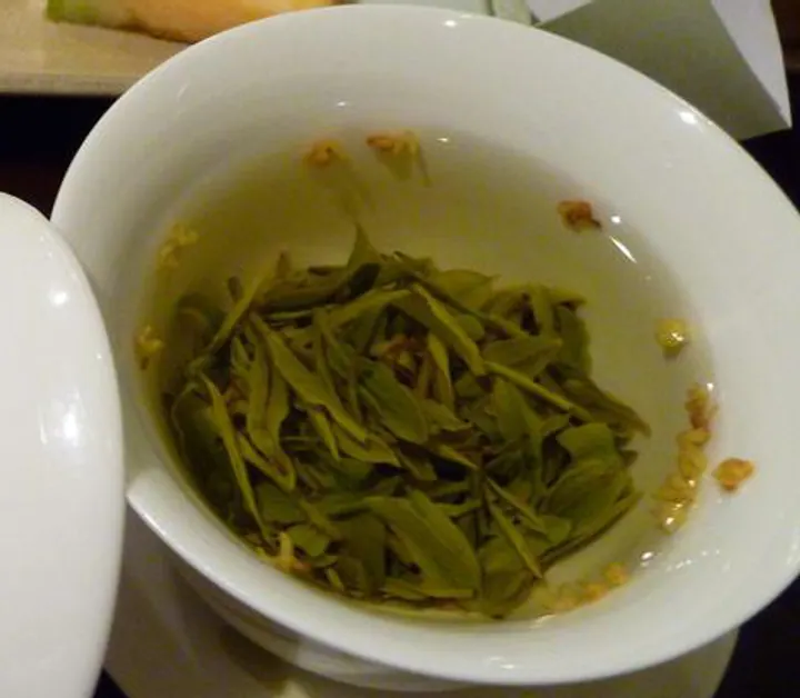 Tea leaves opening in a white porcelain bowl