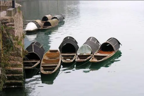 A row of small ferries at the steps, each under a black half-round canopy