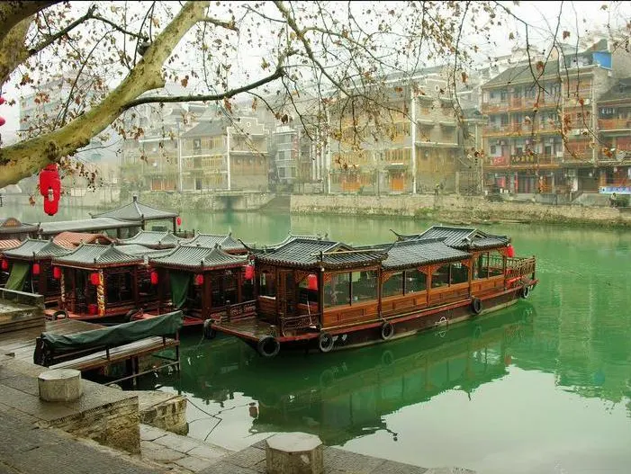 Painted pleasure boats at the stone steps — timber and tiled roofs by day, hung with lights at night