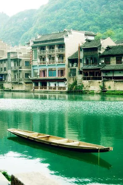 An empty wooden boat on the river, riverside houses behind